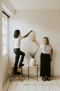 Aesthetic home decor, woman hanging frames on wall