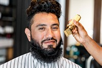 Customer getting a beard trim in a barber shop, small business