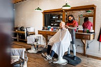 Hair stylist trimming hair of the customer at a barbershop, small business