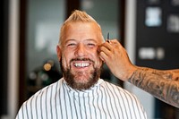 Man getting a haircut from a hair stylist at a barber shop, small business