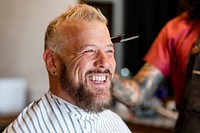 Barber trimming a customer's hair at a barber shop, small business