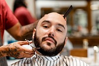 Customer getting a beard trim in a barber shop, small business