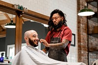 Barber trimming a customer's beard at a barber shop, small business