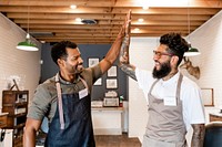 Happy barbers giving high five in a shop