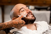 Customer getting a beard trim in a barber shop, small business