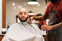 Barber trimming a customer's beard at a barber shop, small business