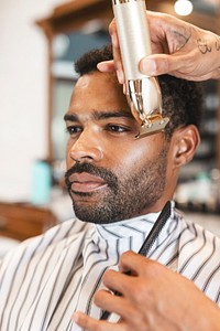 Customer getting a beard trim in a barber shop, small business