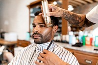 Customer getting a beard trim in a barber shop, small business