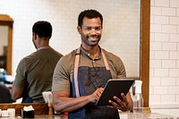 Barber with apron checking queue on tablet, online booking system