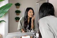 Woman applying face cream in bathroom