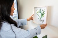 Woman hanging frame on wall, watercolor botanical illustration