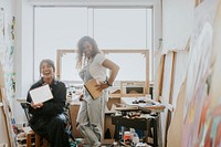 Woman artist friends in a studio with one friend showing a blank digital tablet 