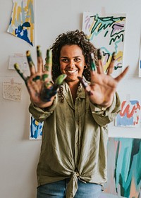 Woman artist showing her hands covered in paint 