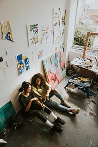 Artist friends sitting on the floor in an art studio 