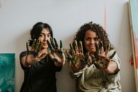 Female artist friends showing their paint covered hands