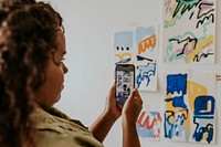 Person taking a photo with phone camera of a mood board on a white wall