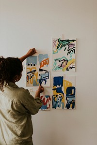 Woman artist putting her abstract artwork on the mood board wall 