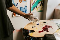 Woman artist mixing paint on a color palette 