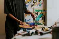 Woman artist mixing paint on a color palette 