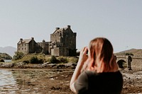 Scottish castle by a pond, tourist taking photos of the scene