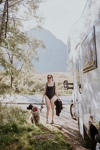 Woman in bathing suit with dog by her campervan