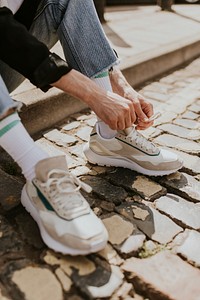 Man tying shoelaces, closeup shot, sitting on a footpath