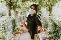 Woman wearing surgical mask carrying a cup of coffee 