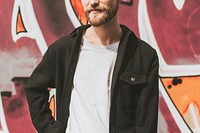 Hipster man on the street in a city by a graffiti wall 