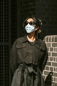 Indian woman wearing mask posing by the brick wall 