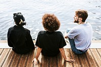 Three diverse friends sitting by the river bank 