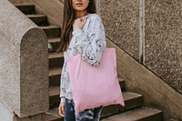 Woman using tote pink bag, standing by the staircase