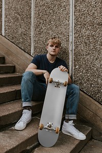 Cool man with gray skateboard sitting on steps