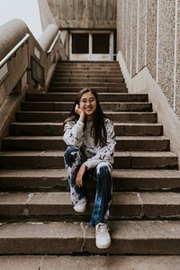 Asian woman in streetwear sitting on staircase