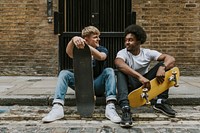 Men with skateboards sitting on sidewalk