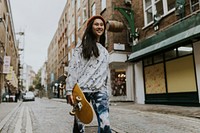 Happy Asian skate walking in city with yellow skateboard