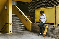 Male skater texting at yellow stairs