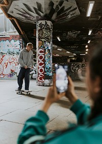 Male skater at skate park, snaps by woman