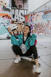 Asian female skater sitting on skateboard