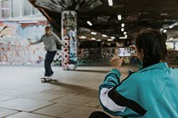 Woman capturing man skating at skate park