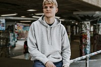 Man in gray hoodie sitting at skate park