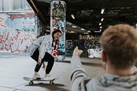 Man recording female skater at skate park