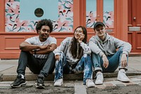 Diverse friends sitting on sidewalk in front of store