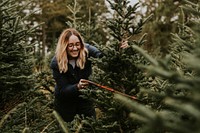 Woman sawing a Christmas tree at a Christmas tree farm 