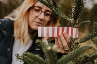 Happy woman wrapping up the tip of a Christmas tree at a Christmas tree farm 