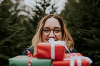 Smiling woman carrying many boxes of Christmas presents