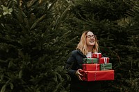 Smiling woman carrying many boxes of Christmas presents