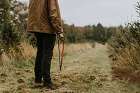 Man carrying a bow saw on a walking patch at a Christmas tree farm 