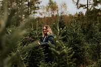 Woman cutting a Christmas tree at a Christmas tree farm 