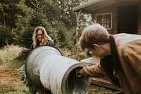 Man and woman wrapping a Christmas tree using the tube machine at a Christmas tree farm 