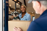 Black woman receiving package delivery, holding a dog image